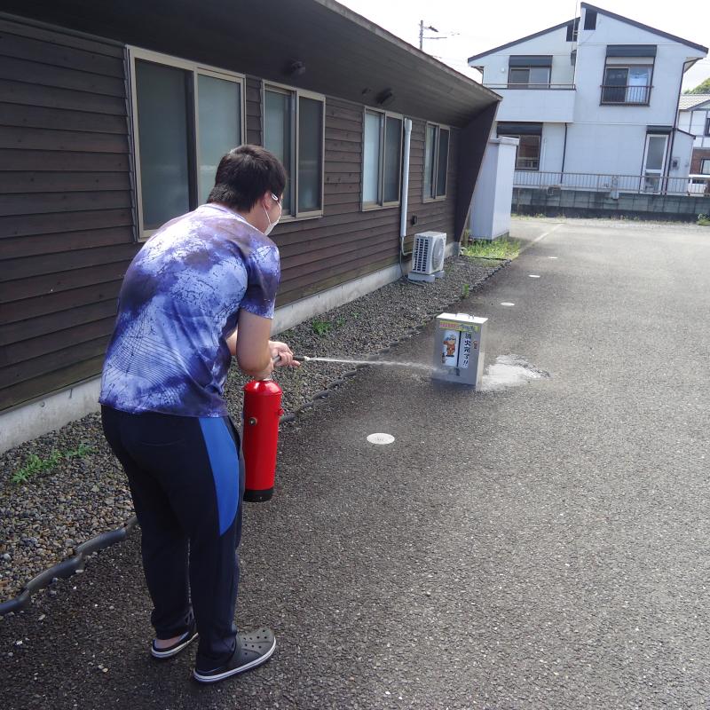 屋外にて水消火器の使用訓練を実施しています